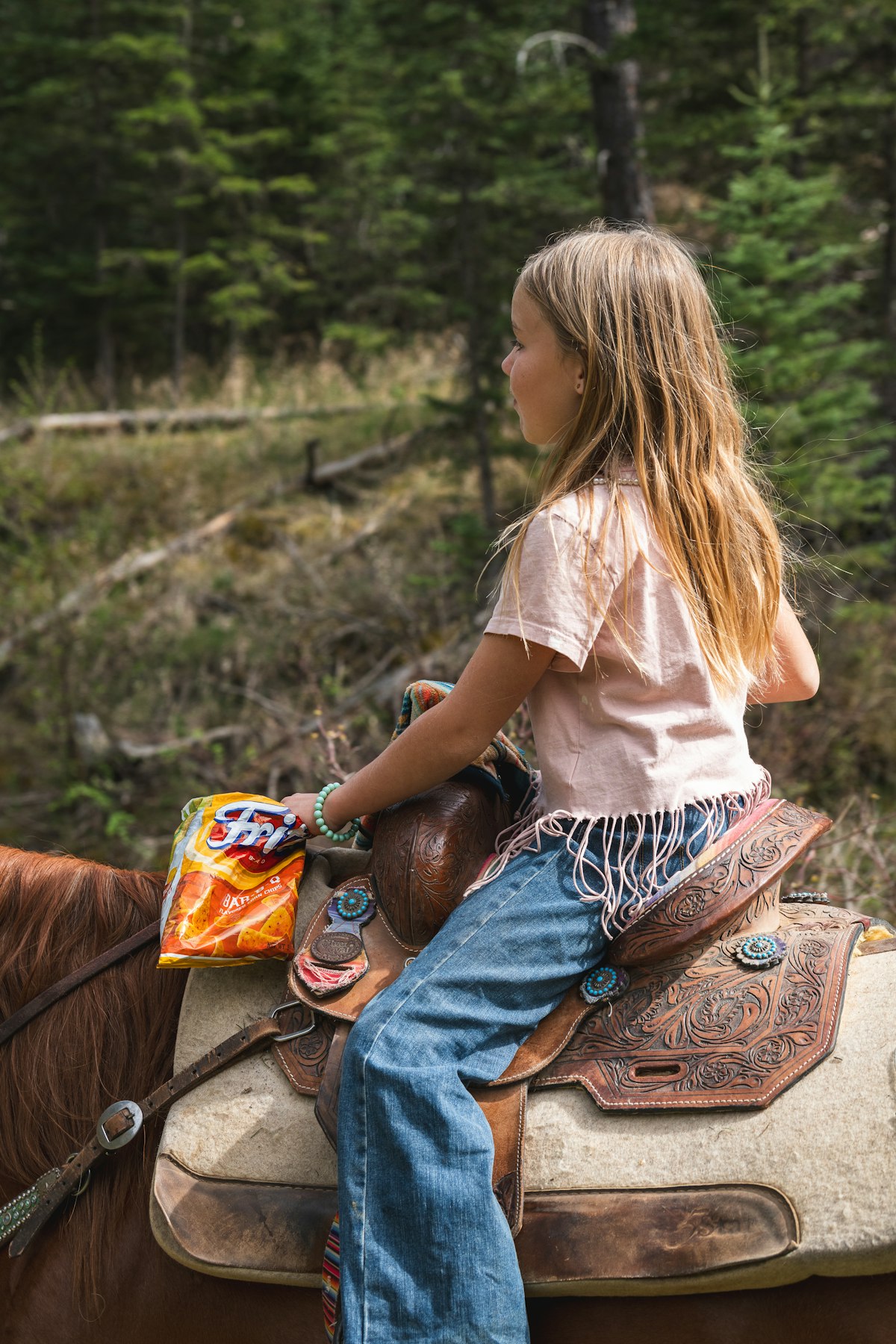 Niña a caballo por un camino de bosque