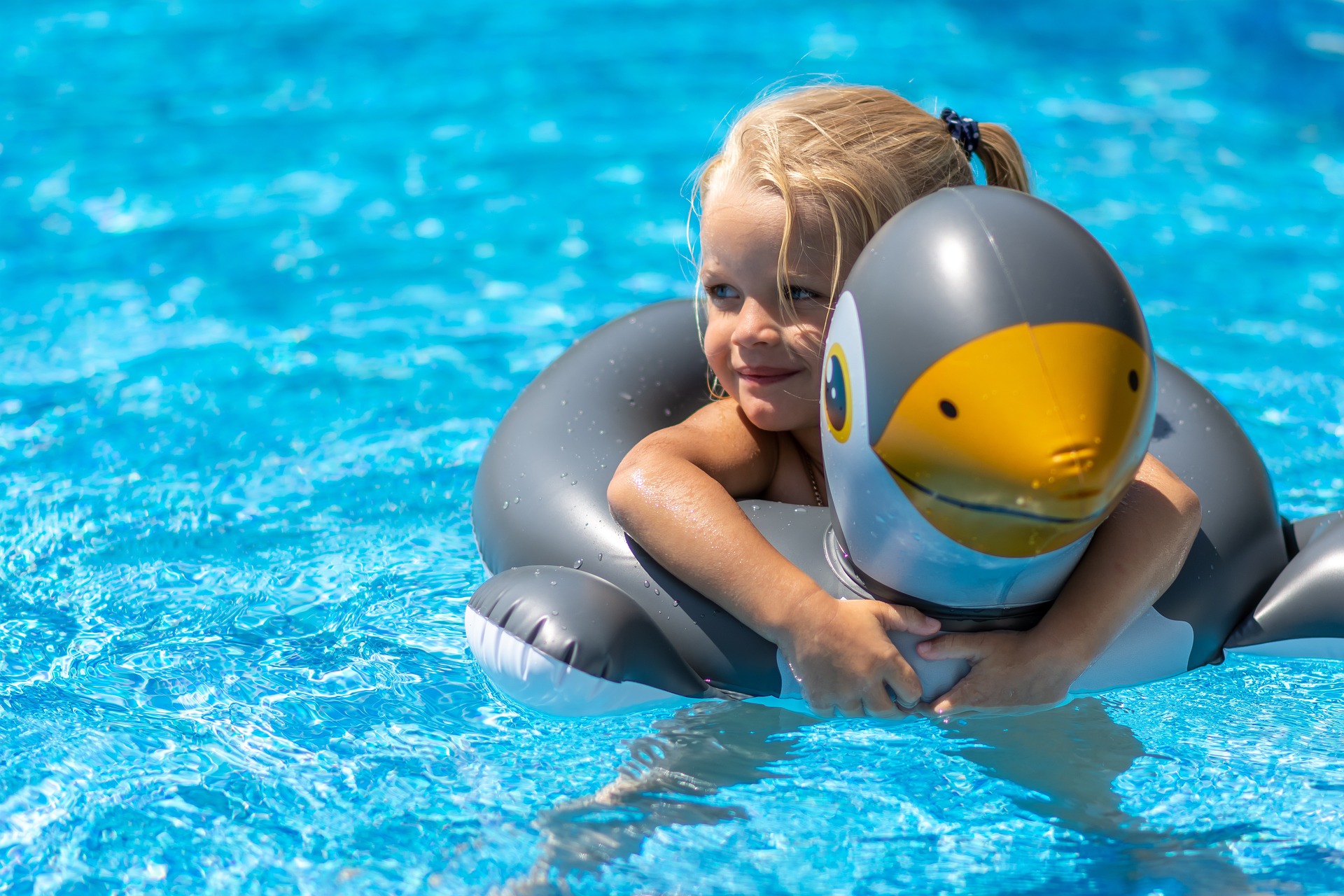 Niña en la piscina con un flotador de pingüino